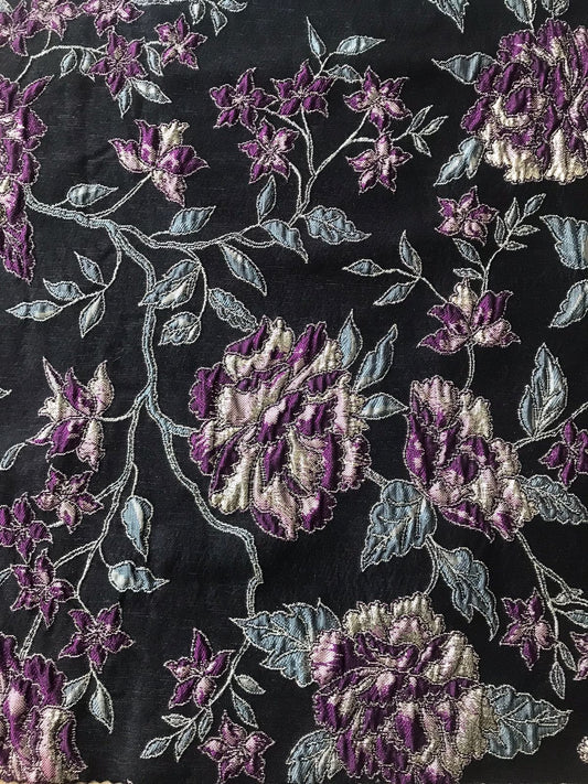 Detalle de textura brocada en flor morada sobre jacquard negro con contorno plateado