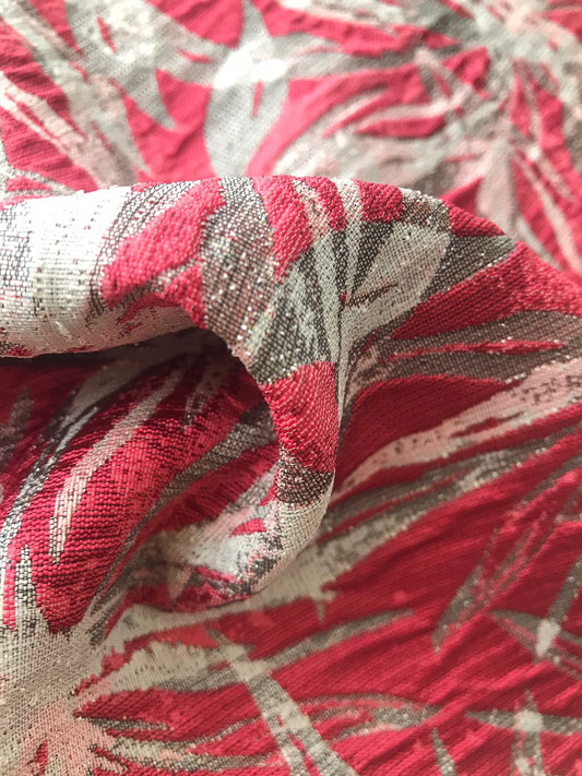 Detalle de motivo floral geométrico rojo coral y blanco en tela jacquard con relieve