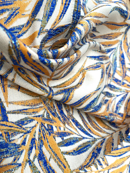 Jacquard tropical de hojas de palma azul y mostaza sobre fondo blanco, tela drapeada