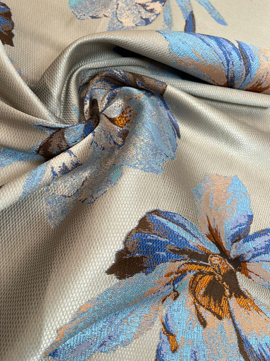 Jacquard floral gris perla con flores azul y naranja estilo acuarela, tela doblada