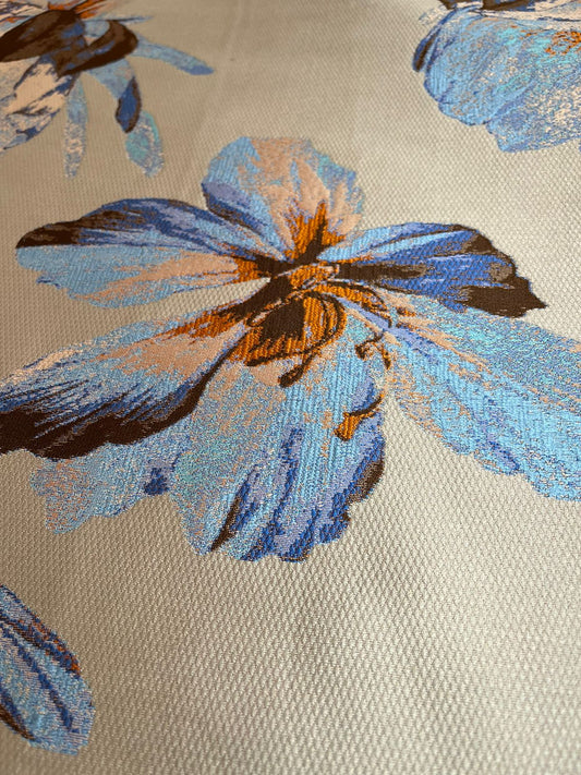 Detalle de flor azul y naranja con efecto acuarela en jacquard satinado gris
